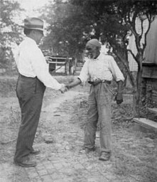 Folk song collector John A. Lomax, Sr., (1867-1948) shaking hands with 